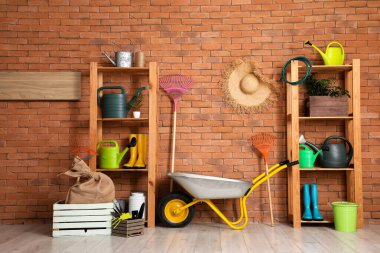 El arabası, raf üniteleri ve ahır duvarının yanındaki bahçe aletleri.