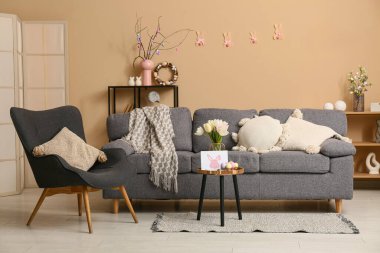 Paskalya için dekore edilmiş oturma odasının içinde kanepe, koltuk ve masa var.