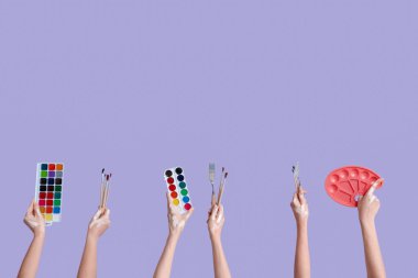 Leylak arka planında sanatçı malzemeleri olan kadın eller.