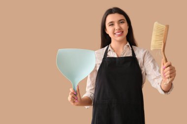 Bej arka planda faraş ve fırçayla genç bir kadın.