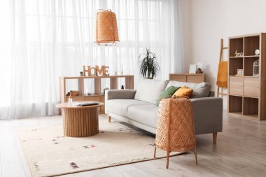 Gri kanepesi, ahşap masası ve rafları olan rahat bir oturma odası.