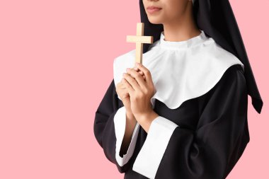 Pembe arka planda haç çizen genç rahibe