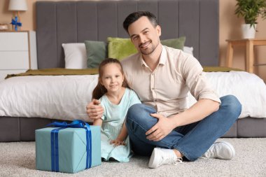 Baba ve kızı yatak odasındaki hediye kutusunun yanında oturuyorlar. Babalar günü kutlaması.