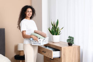 Güzel, genç, mutlu, Afro-Amerikan bir kadın evde temiz giysiler giyiyor.