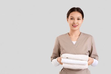 Hafif arka planda havluları olan Asyalı kadın masaj terapisti.