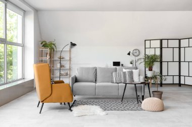 Gri kanepeli, masalı ve koltuklu aydınlık oturma odasının içi.