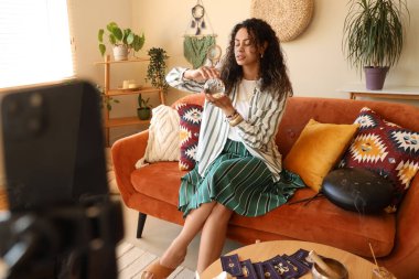 Evinde kristal küre kayıt videosu olan genç bir Afro-Amerikan cadı.