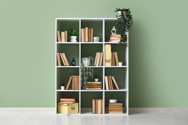 Modern shelving unit with books and home decor near green wall