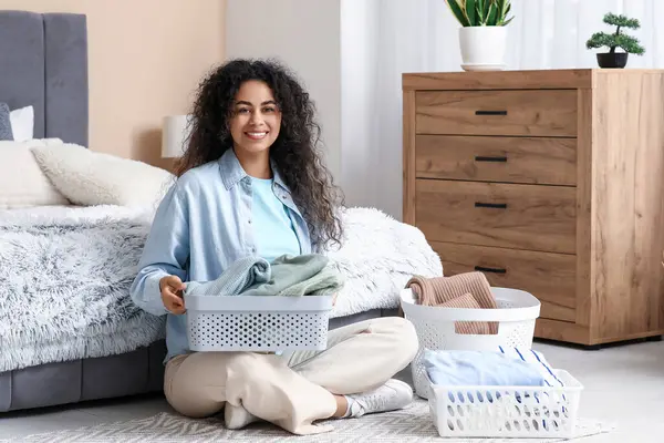 Güzel, genç, mutlu, Afro-Amerikan bir kadın. Elinde sepetler, temiz giysileri katlıyor.