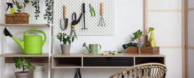 Beyaz duvarın yanında bahçe aletleri ve bitkilerle dolu bir işyeri.