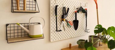 Çalışma odasındaki ışık duvarında bahçe aletleri olan tahta ve raflar