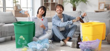 Evlerinde çöp kutularını düzenleyen genç bir çift. Geri dönüşüm kavramı