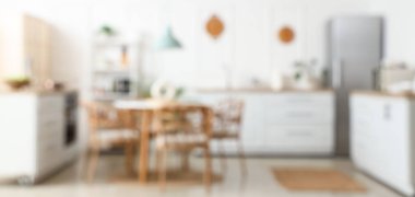 Beyaz tezgahlı, raflı ve yemek masalı aydınlık mutfağın bulanık görüntüsü