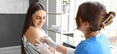 Genç hamile kadın klinikte aşıdan sonra yama yaptırıyor.