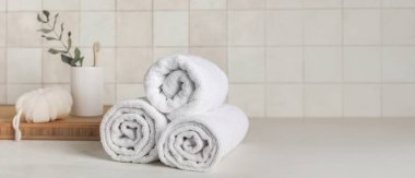 Yuvarlanmış temiz havlular, banyo süngeri ve diş fırçası açık arkaplan ve metin için yer var.