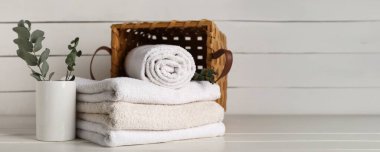 Temiz havlu yığını, hasır sepet ve okaliptüs dalları hafif ahşap zemin üzerinde metin için alan