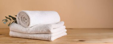 Temiz havlular ve okaliptüs dalı ahşap masa üzerinde bej arkaplan ve metin için boşluk  