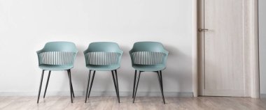 Beyaz duvarın yanındaki modern sandalyeler.