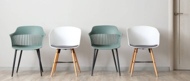 Beyaz duvarın yanındaki modern sandalyeler.