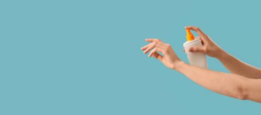 Kadının elleri mavi arkaplana güneş kremi sürerken metin için boşluk bırakıyor