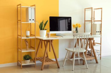 Modern bilgisayar, güzel narsisli çiçekler ve kahve ile şık bir ofis.