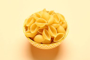 Sarı arka planda çiğ koni makarnalı kase.