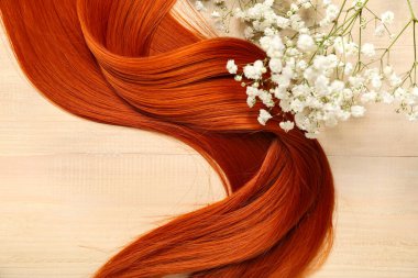 Açık ahşap arka planda güzel çigila çiçekleri olan kızıl saçlı, yakın plan.