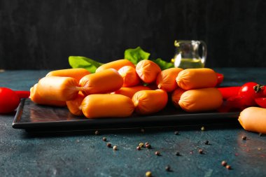 Lezzetli kaynamış sosis ve koyu arkaplanda kırmızı biber.