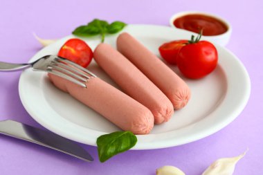 Lezzetli sosis, fesleğen ve leylak arkaplanda domates.