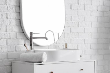 Banyodaki çekmecelerin üzerinde banyo aksesuarları olan beyaz lavabo.