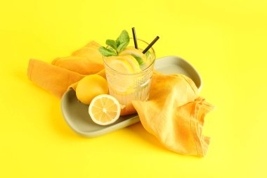 Sarı zemin üzerinde taze limonata olan tabak ve cam.