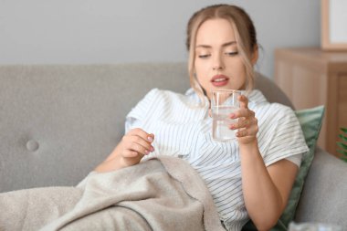 Evinde bir bardak suda çözünmüş tabletle genç bir kadın.