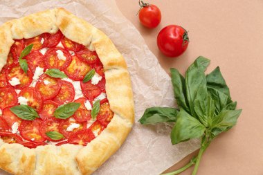 Lezzetli domates galeti ve bej arka planda fesleğen içeren kağıt fırını.