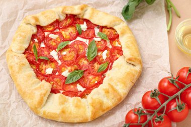 Lezzetli domates galeti ve bej arka planda fesleğen içeren kağıt fırını.