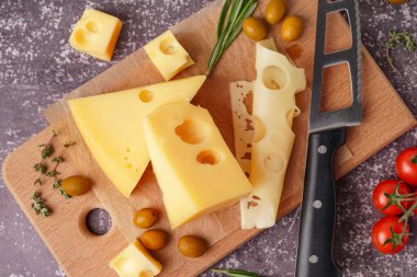 Gri zemin üzerinde İsviçre peyniri ve zeytin parçaları olan tahta