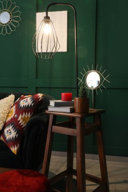 Oturma odasının içinde yeşil kanepe, puf, tabure ve parlayan lamba.