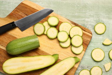 Yeşil ahşap zemin üzerinde taze kabak dilimleri olan tahta.