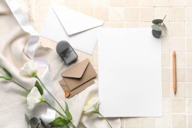 Boş kartlı kompozisyon, zarflar, nişan yüzüğü ve bej kaplamalı güzel östoma çiçekleri.