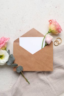 Zarflı kompozisyon, boş kart, alyans ve açık arkaplanda östoma çiçekleri