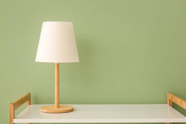 Masa lambası yeşil duvarın yanındaki beyaz rafta.