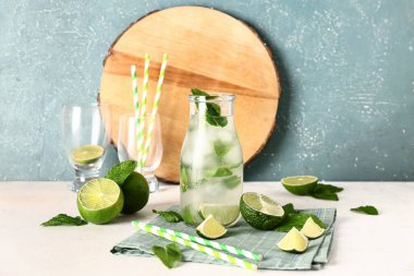 Bir şişe soğuk mojito, nane yaprağı, limon ve pipet.