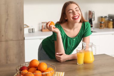 Mutfakta portakal suyu ve meyve suyu olan genç bir kadın.