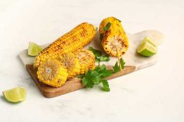 Beyaz arka planda lezzetli ızgara mısır koçanları ve maydanozlu pano.