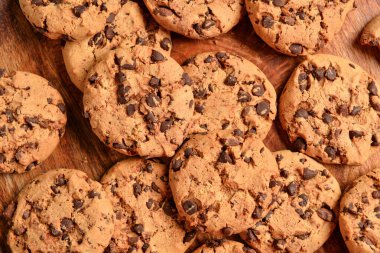 Tahta arka planda çikolata parçalı lezzetli kurabiyeler.