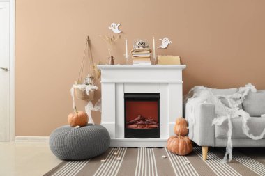 İçinde şömine, gri kanepe ve Cadılar Bayramı süslemeleri olan festival salonu.