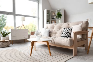 Konforlu kanepe ve beyaz mobilyalarla aydınlık oturma odasının içinde.