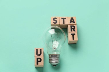 Sözcükler STARTUP ve yeşil arkaplanda ampul
