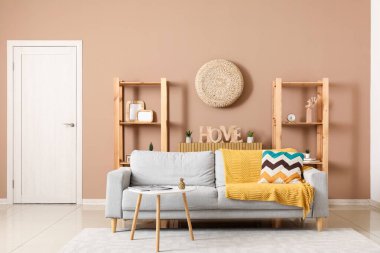 Gri kanepesi, masası ve raf ünitesi olan şık bir oturma odası.