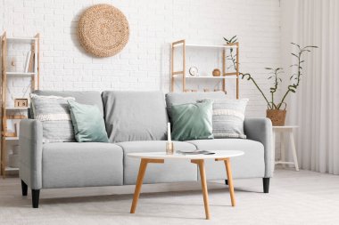 Gri kanepe, masa ve raf üniteleriyle modern oturma odasının içinde.