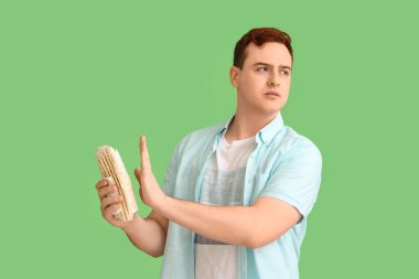 Genç adam yeşil arka planda donör kebap yemeyi reddediyor.